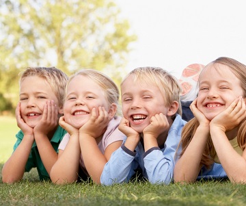 Four children laying in the grass smiling